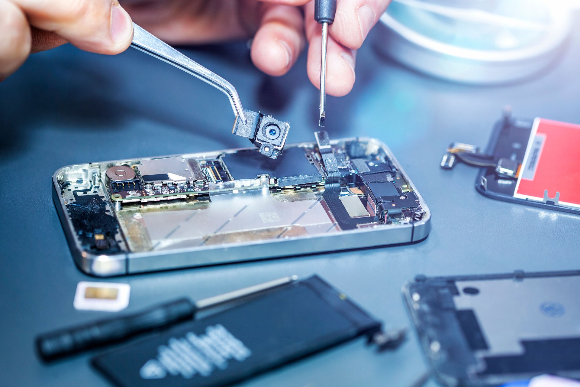 Serviceman repairs the damaged camera on the smartphone